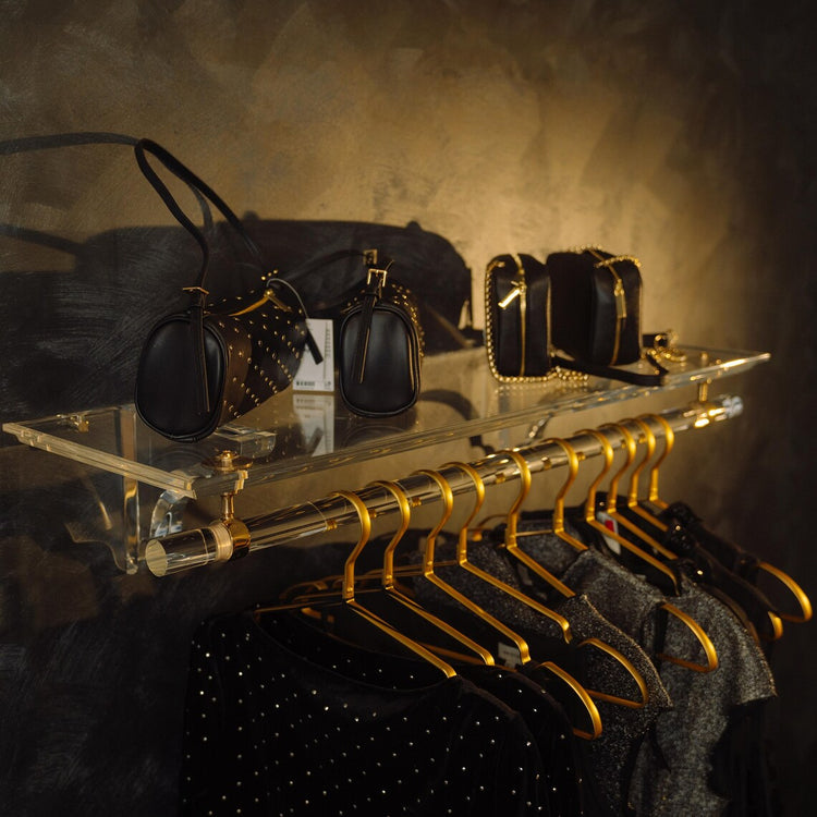 Clear acrylic wall-mounted clothing rack with gold accents