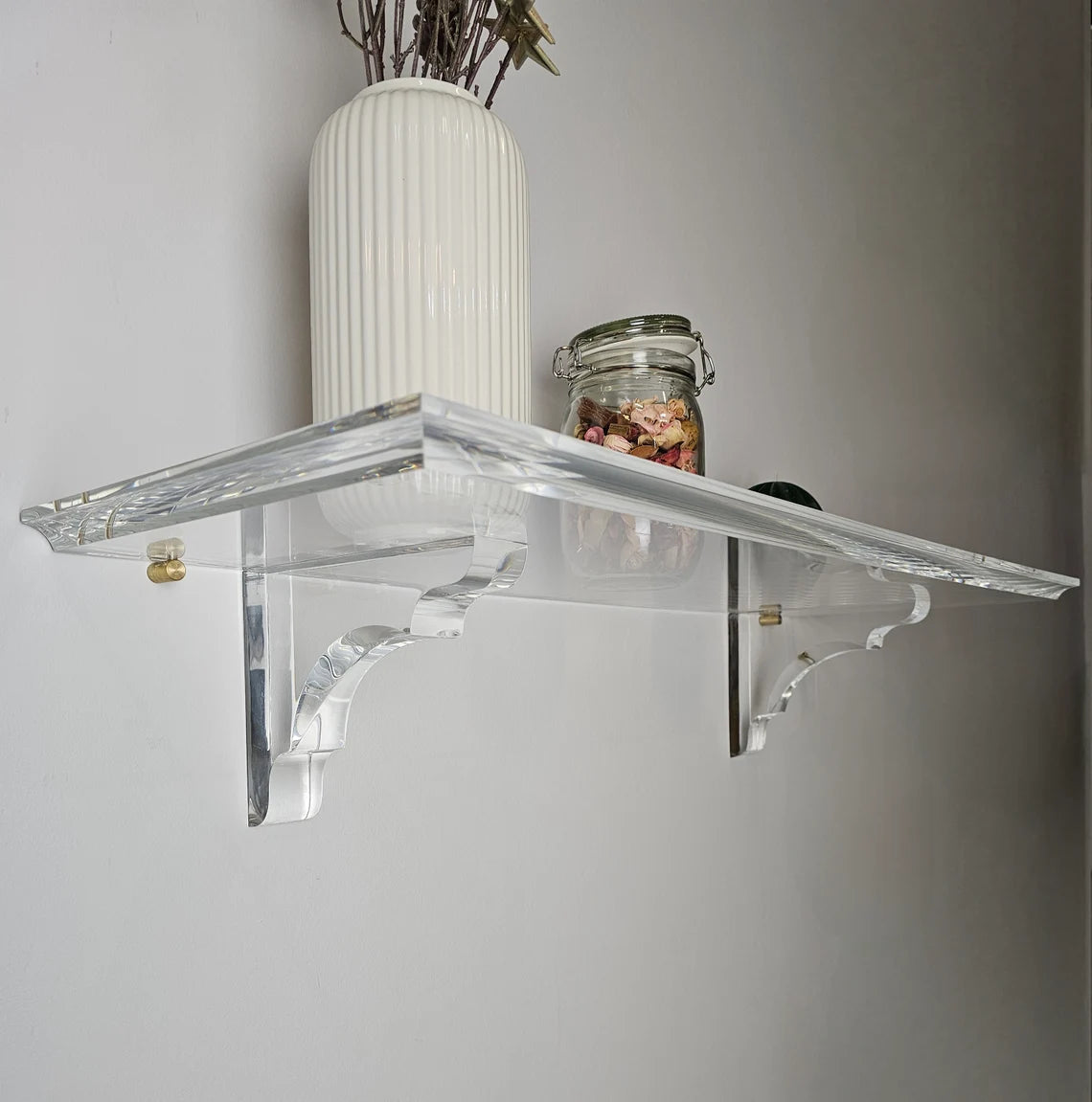 A clear acrylic floating shelf with two mounting brackets