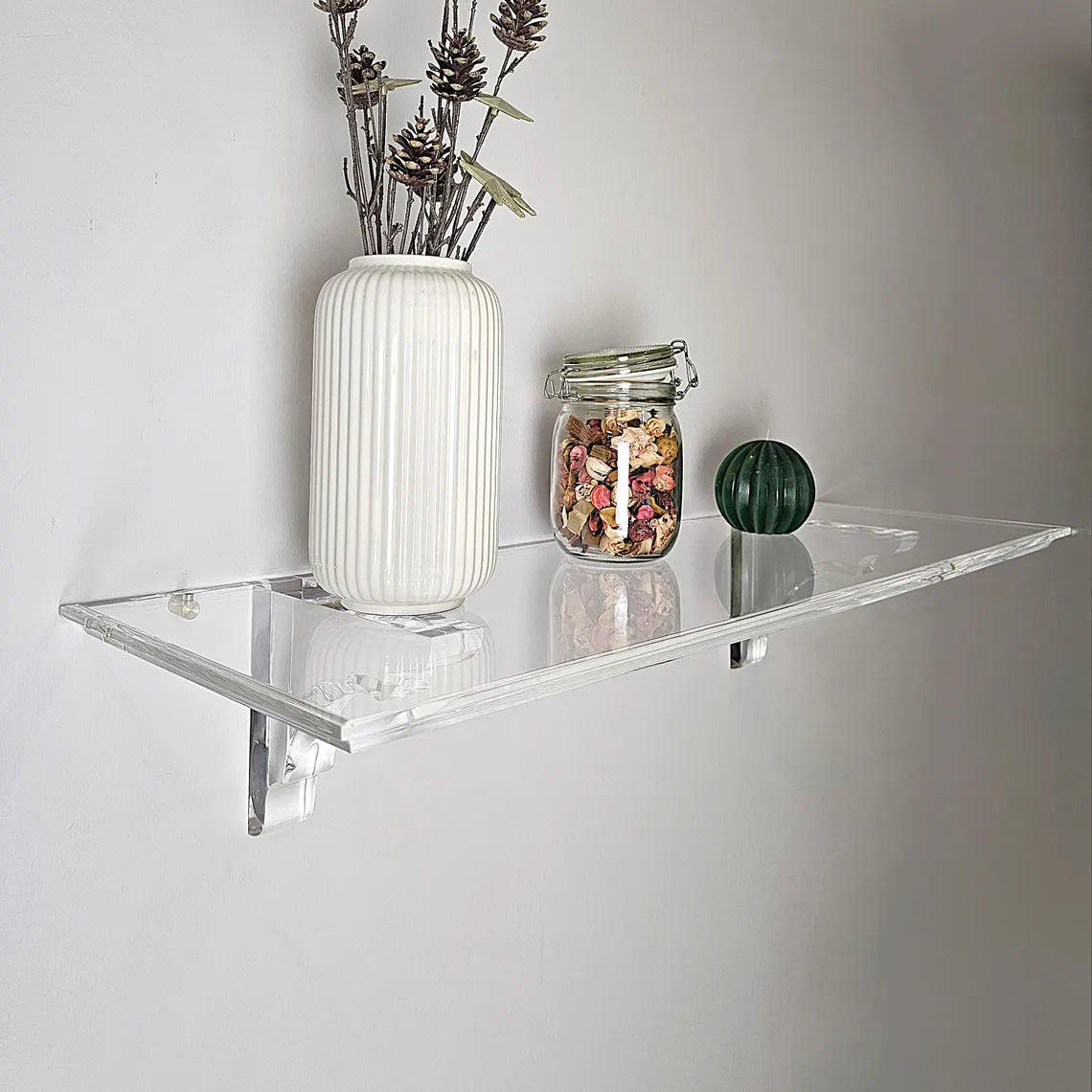 A clear acrylic floating shelf with two mounting brackets