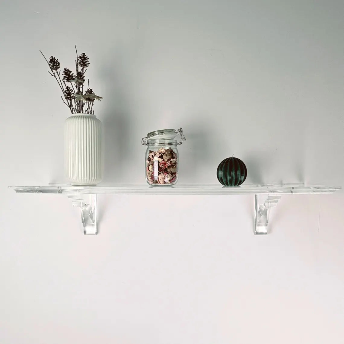 A clear acrylic floating shelf with two mounting brackets