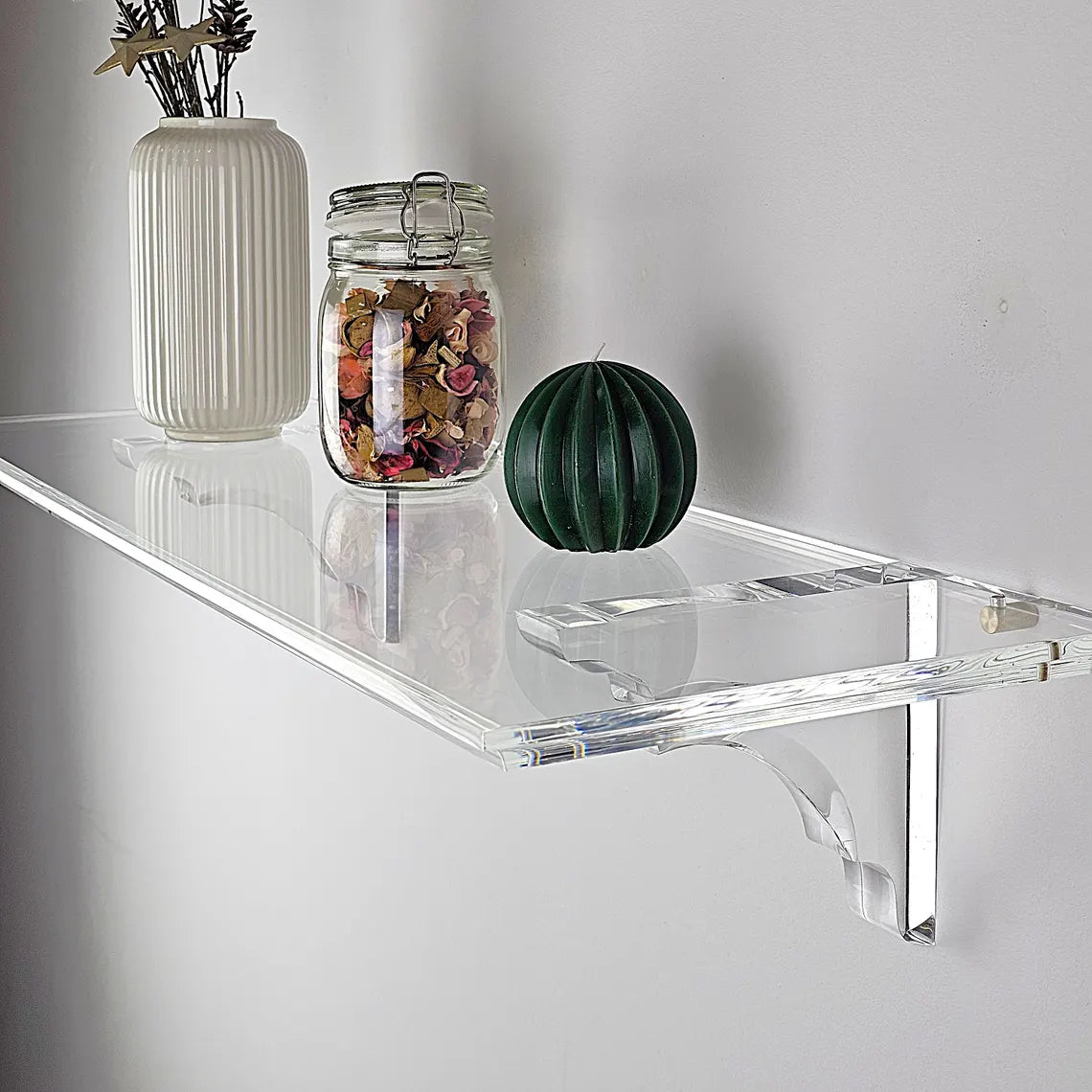 A clear acrylic floating shelf with two mounting brackets
