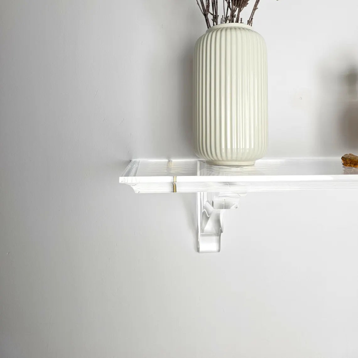 A clear acrylic floating shelf with two mounting brackets