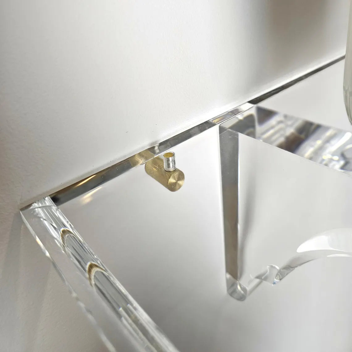 A clear acrylic floating shelf with two mounting brackets