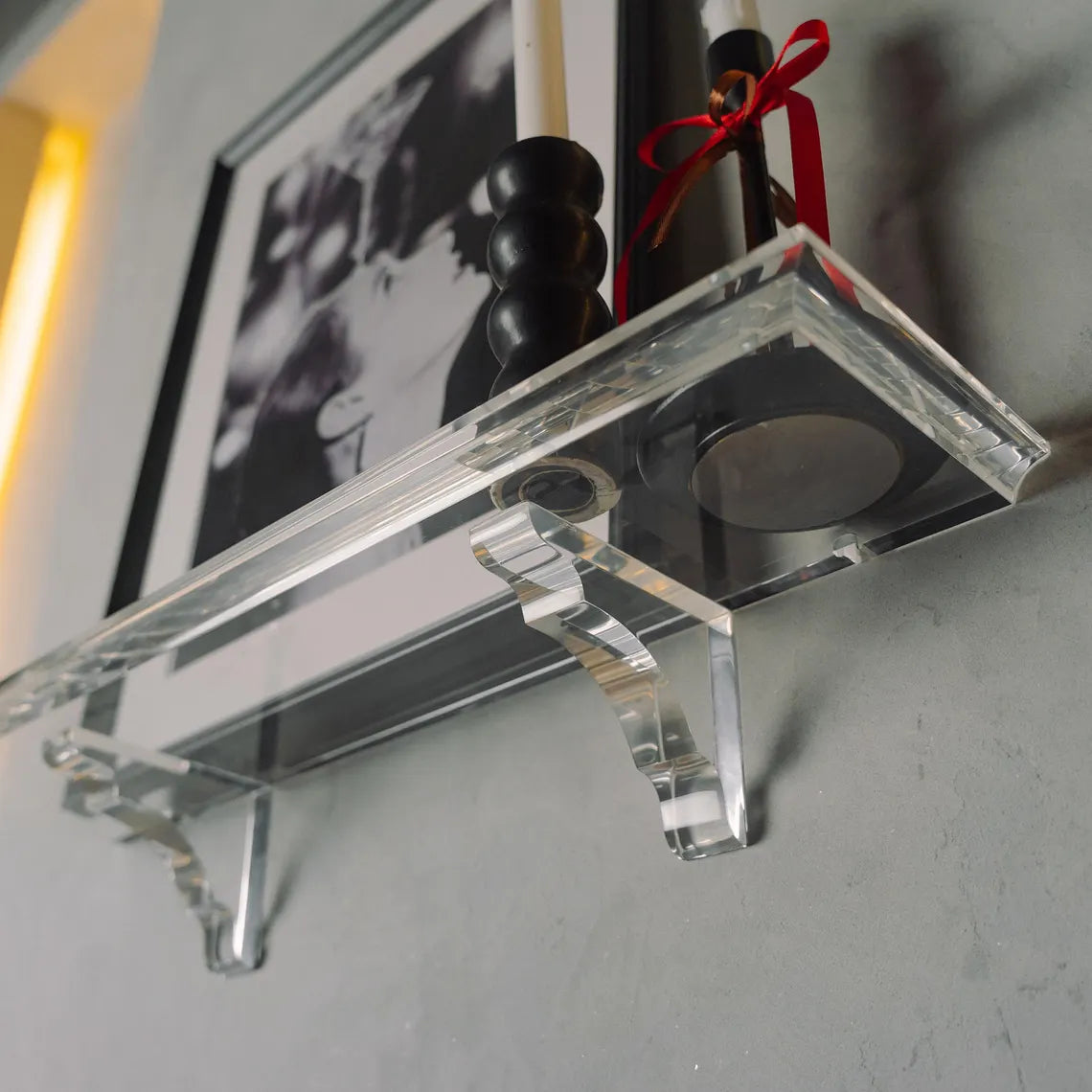 A clear acrylic floating shelf with two mounting brackets