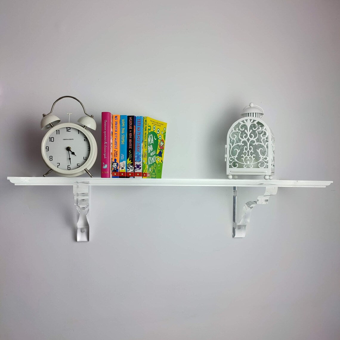 A clear acrylic floating shelf with two mounting brackets