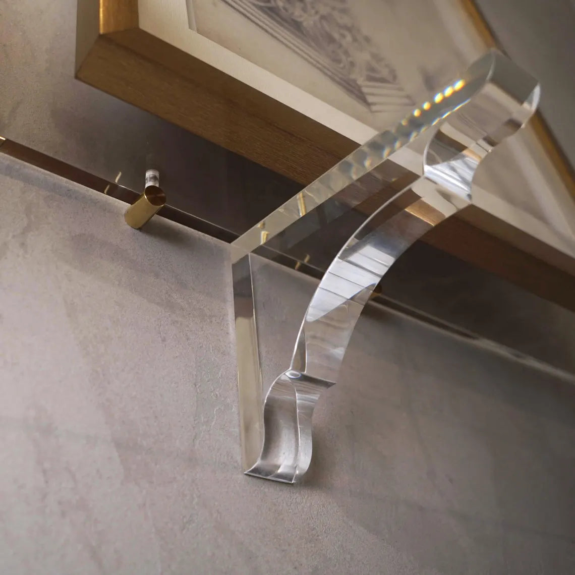 A clear acrylic floating shelf with three mounting brackets