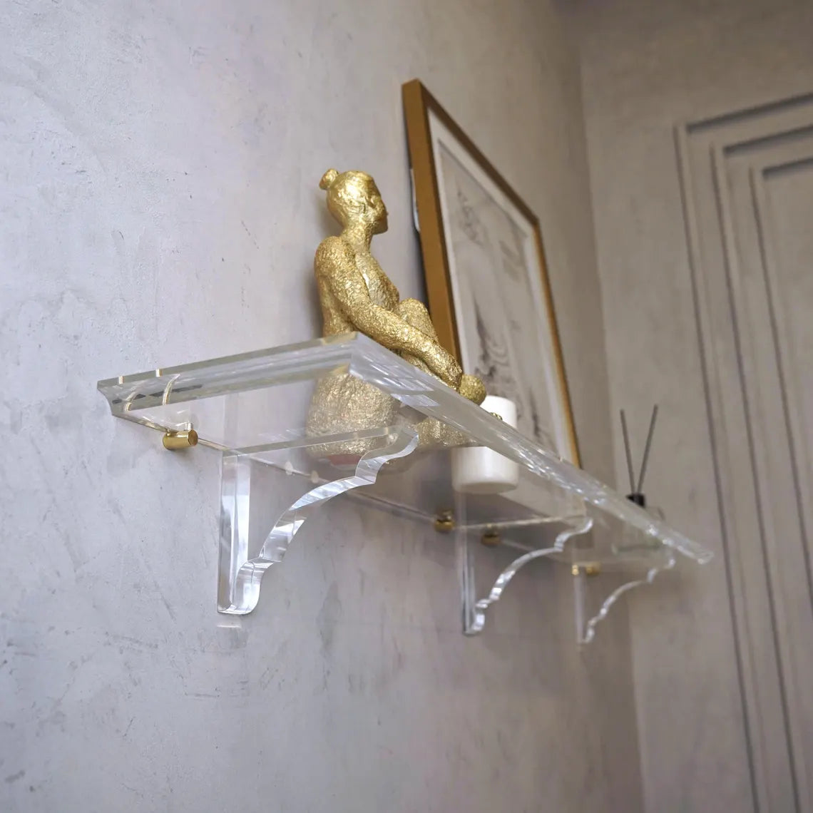 A clear acrylic floating shelf with three mounting brackets