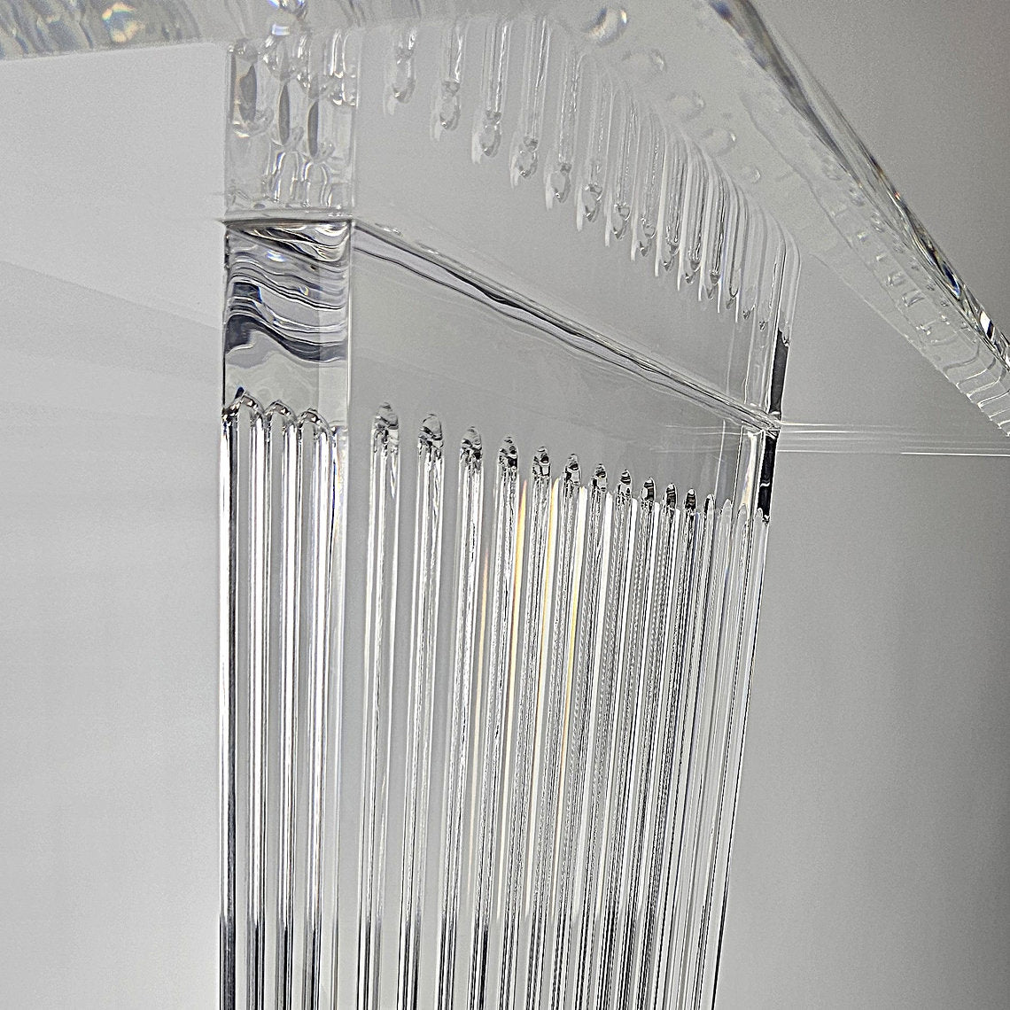 Sculptural acrylic table base with fluted design and reflective surface