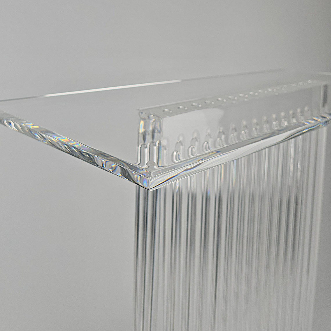 Sculptural acrylic table base with fluted design and reflective surface