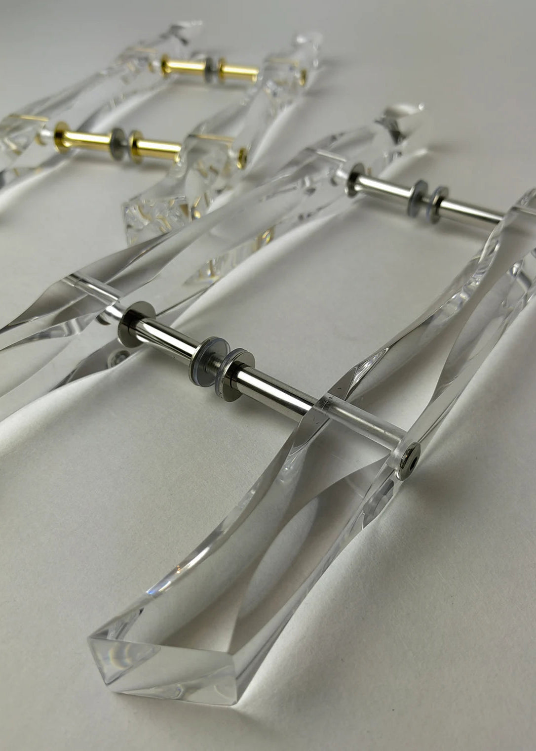 Clear acrylic door pull with flowing edges and chrome or gold accents