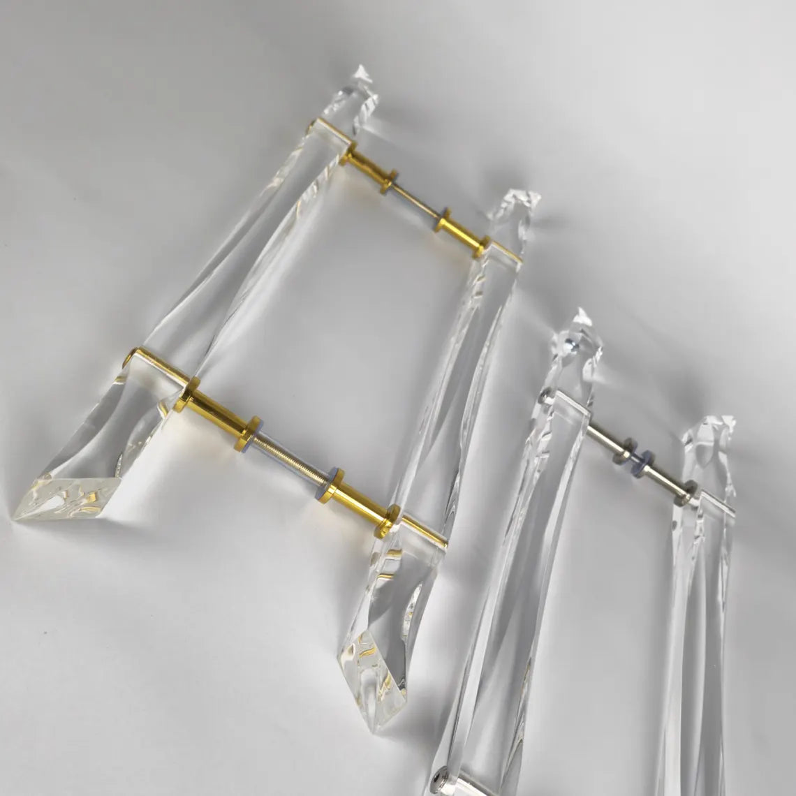 Clear acrylic door pull with flowing edges and chrome or gold accents