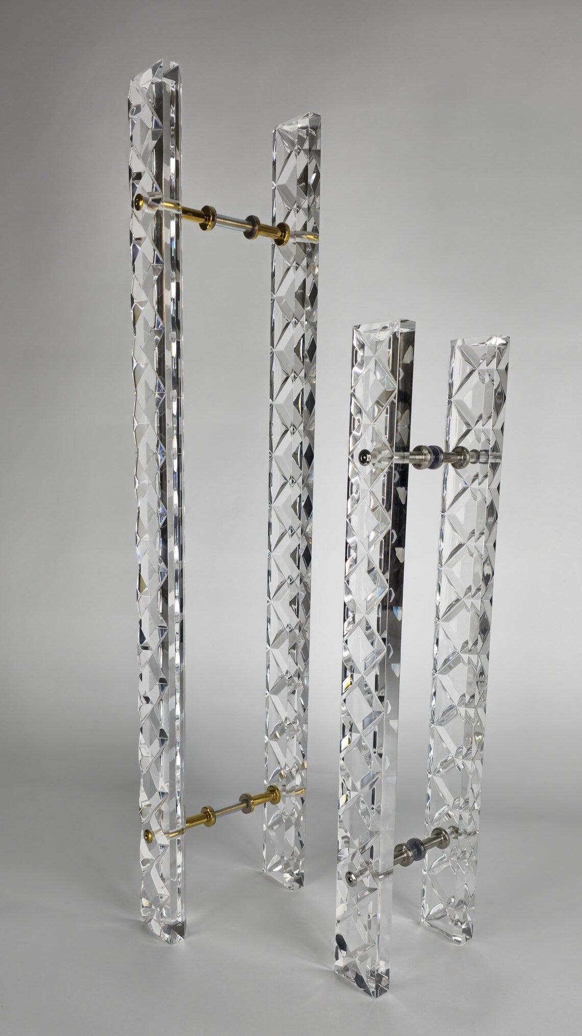 Clear acrylic door pull with a criss-cross pattern and chrome or gold accents