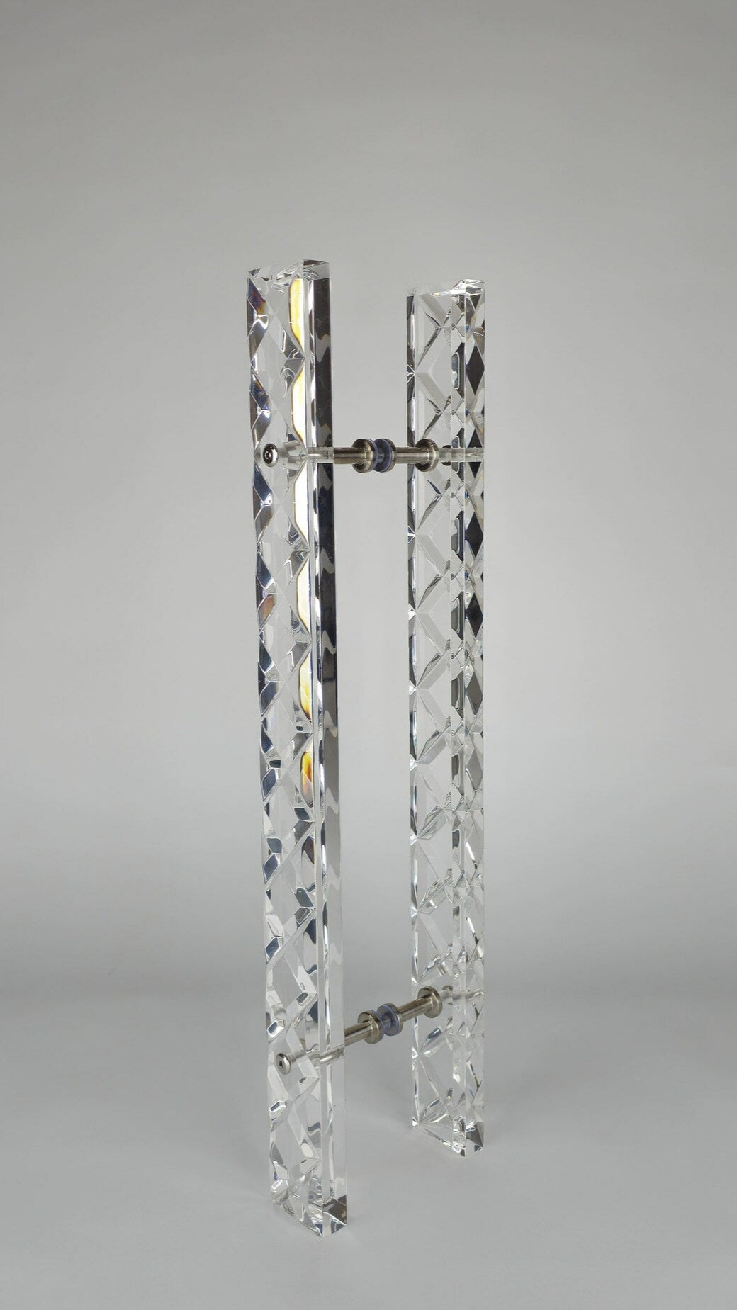 Clear acrylic door pull with a criss-cross pattern and chrome or gold accents