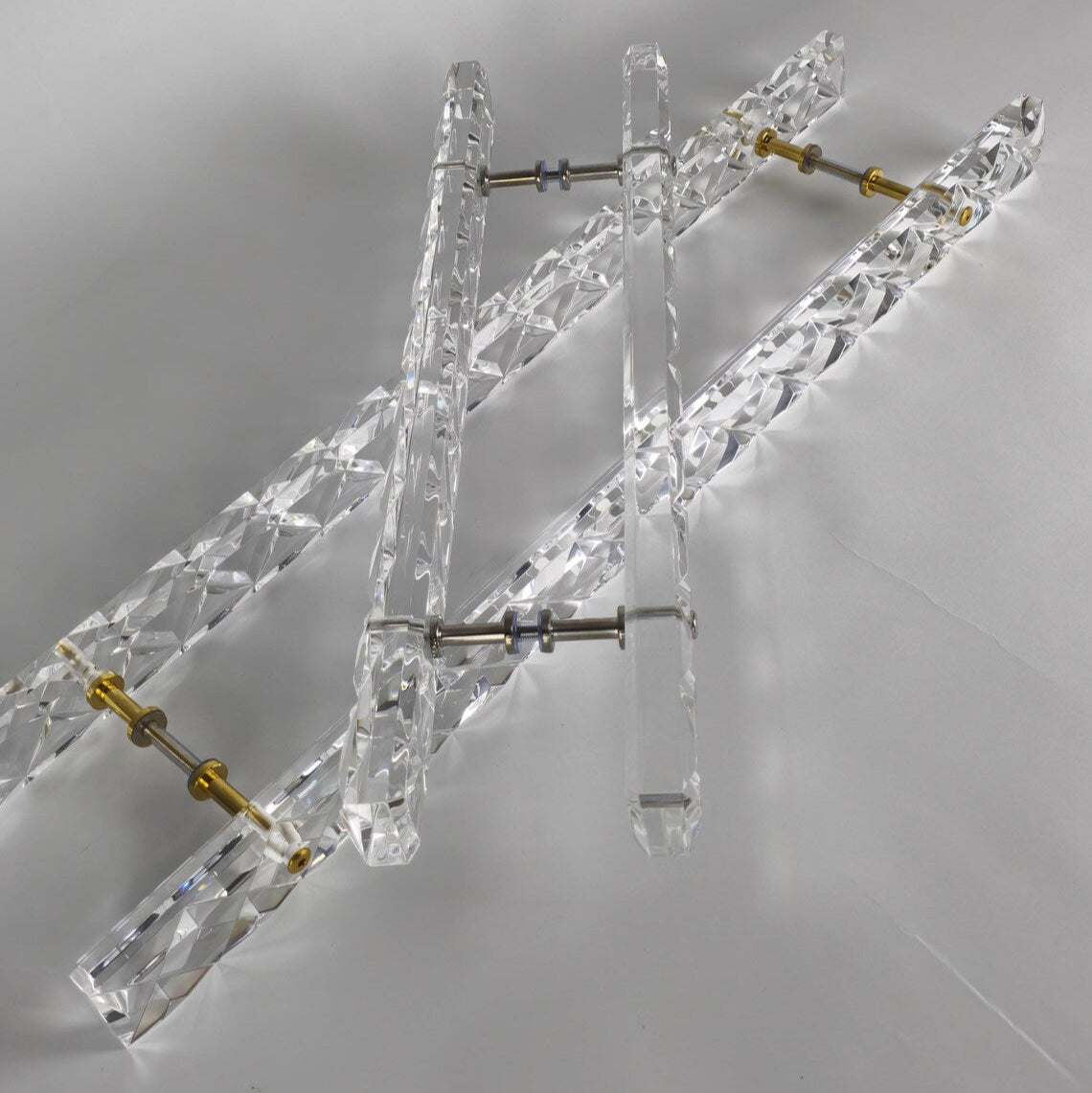 Clear acrylic door pull with a criss-cross pattern and chrome or gold accents