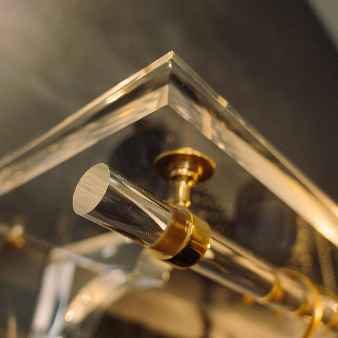 A clear acrylic wall-mounted floating clothing rack with gold accents