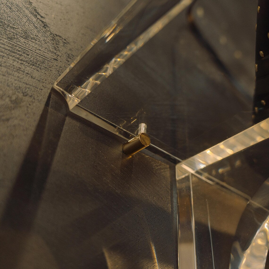 A clear acrylic wall-mounted floating clothing rack with gold accents