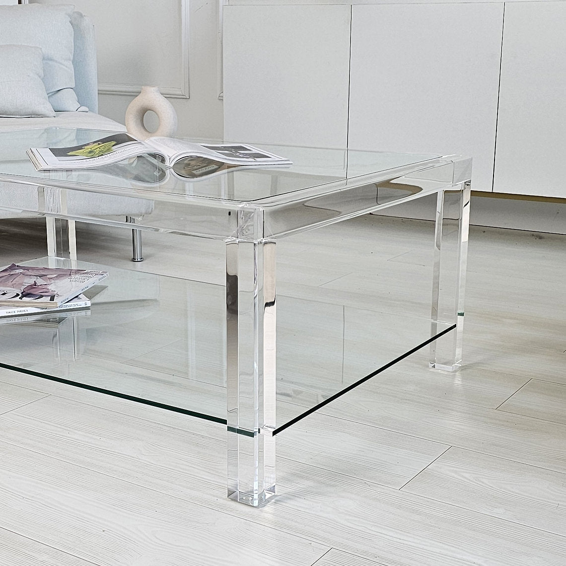 Clear acrylic coffee table with a minimalist style and lower shelf