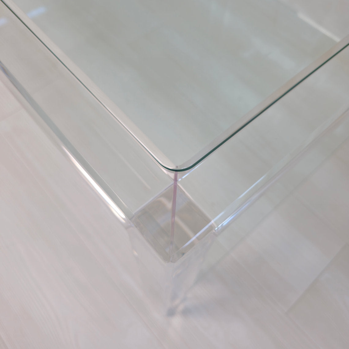 Clear acrylic coffee table with a minimalist style and lower shelf