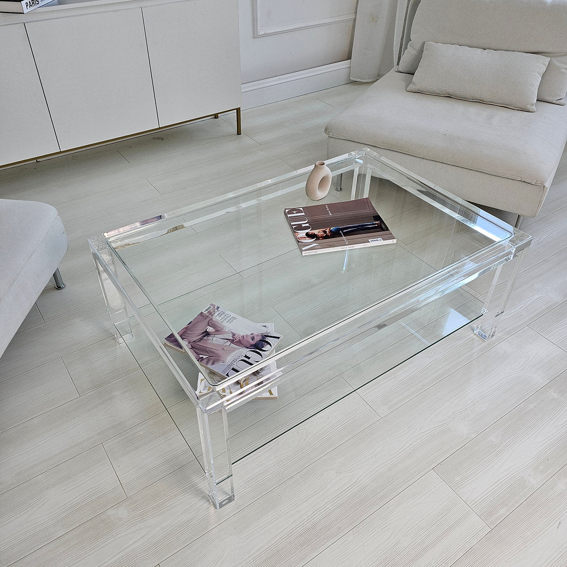 Clear acrylic coffee table with a minimalist style and lower shelf
