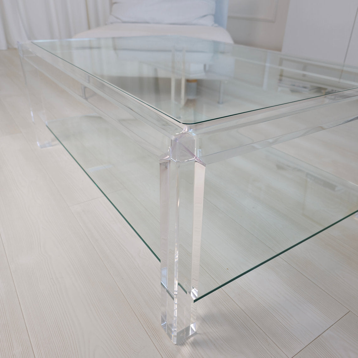 Clear acrylic coffee table with a minimalist style and lower shelf