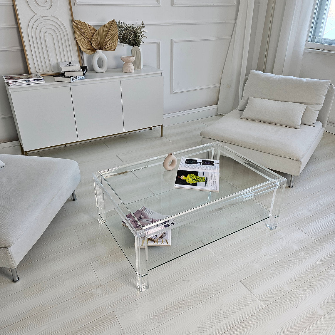 Clear acrylic coffee table with a minimalist style and lower shelf