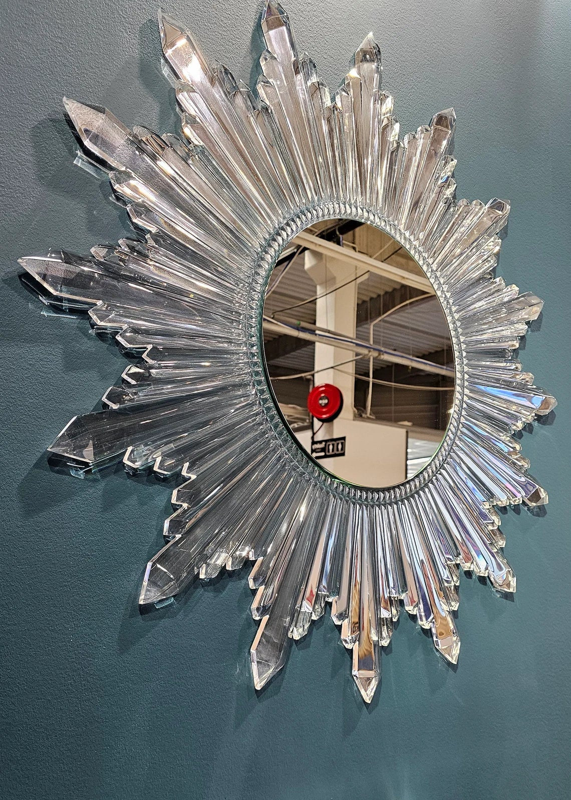 Circular sunburst wall mirror with clear acrylic crystals radiating from the center