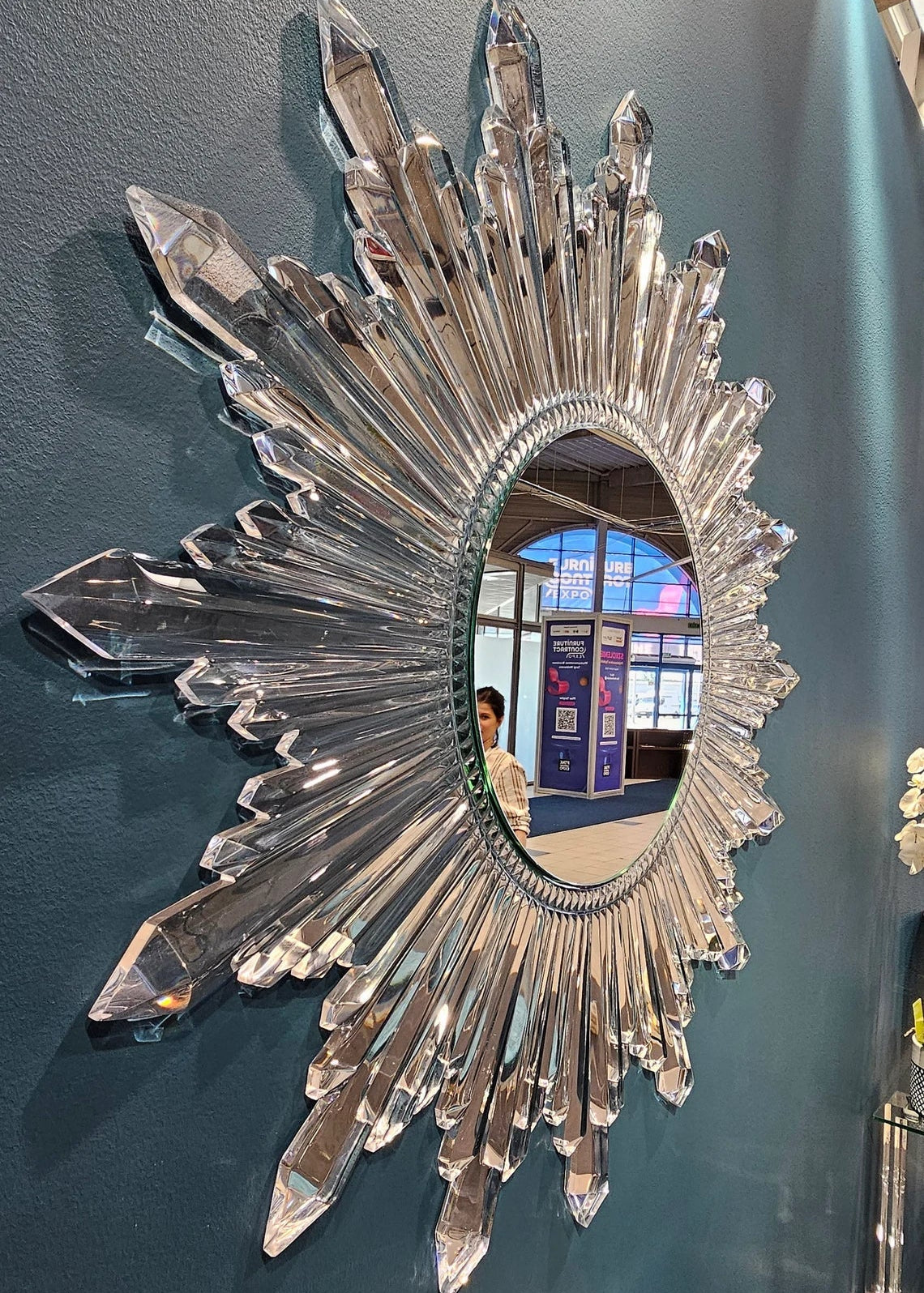 Circular sunburst wall mirror with clear acrylic crystals radiating from the center