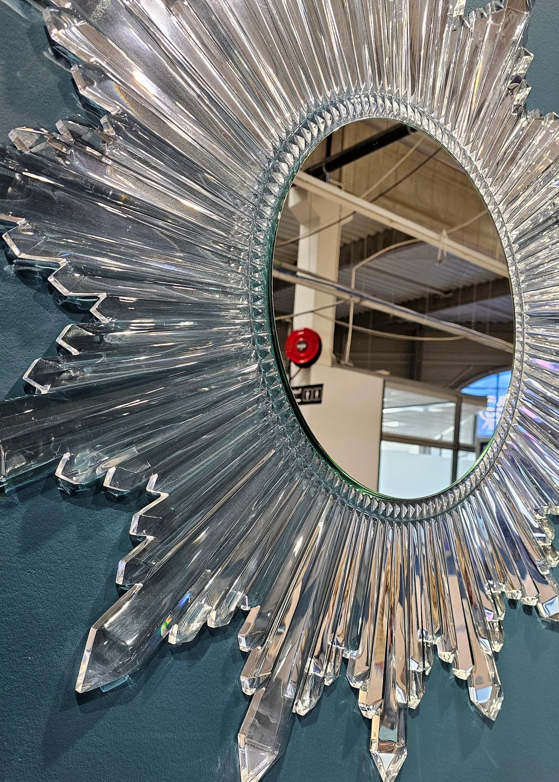 Circular sunburst wall mirror with clear acrylic crystals radiating from the center