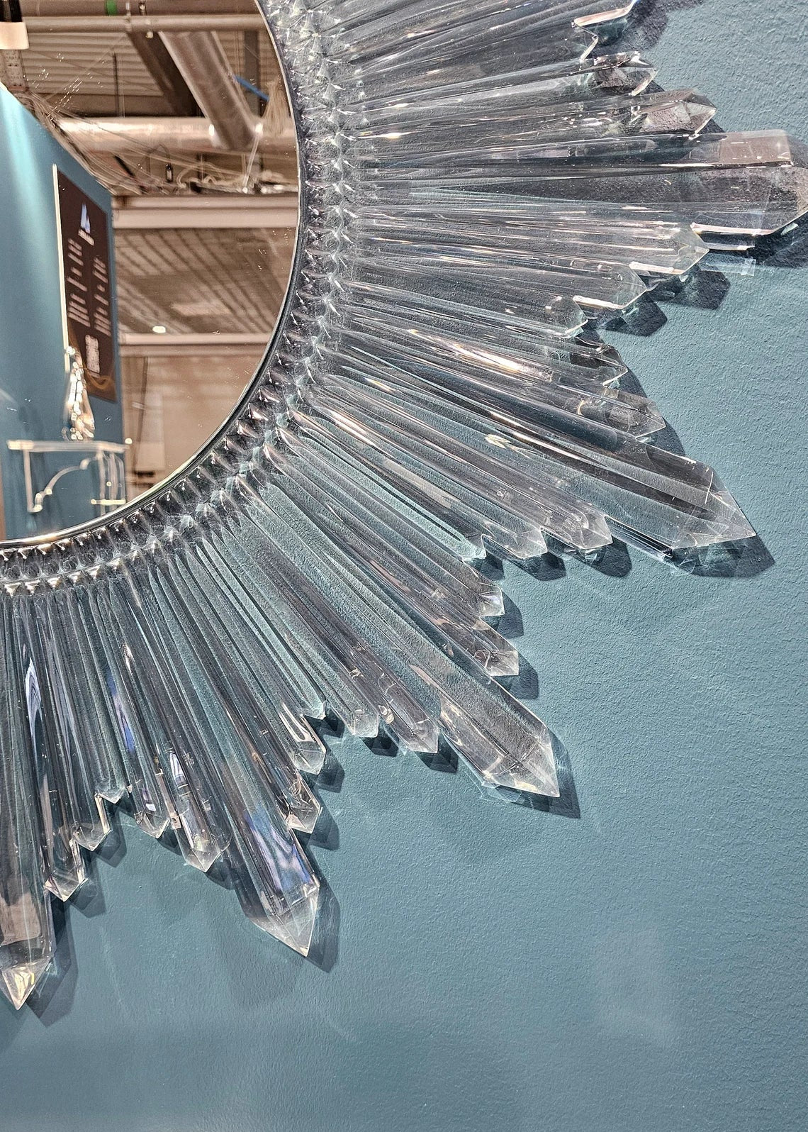 Circular sunburst wall mirror with clear acrylic crystals radiating from the center