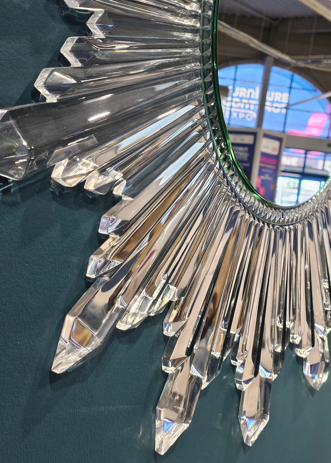 Circular sunburst wall mirror with clear acrylic crystals radiating from the center