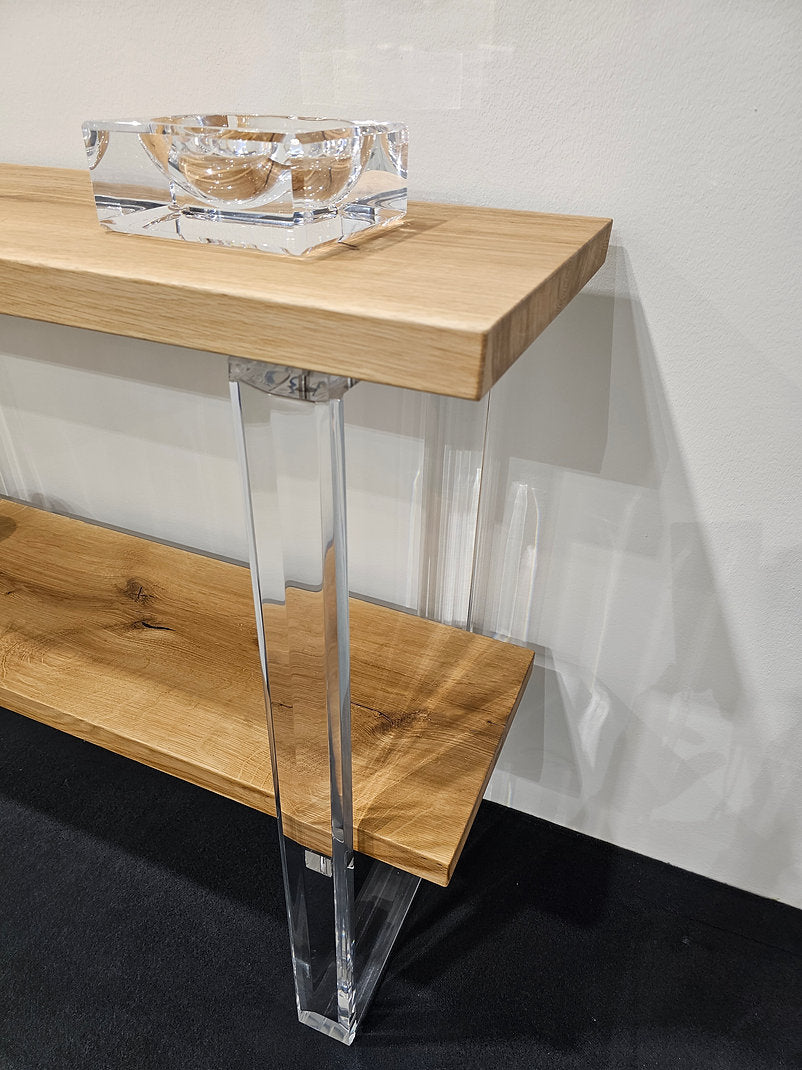 Clear acrylic console table with a light wood top and shelf