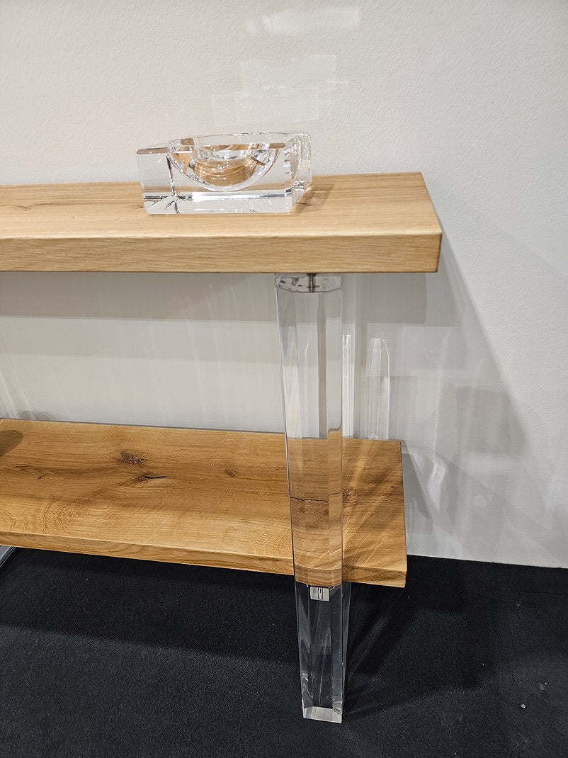 Clear acrylic console table with a light wood top and shelf