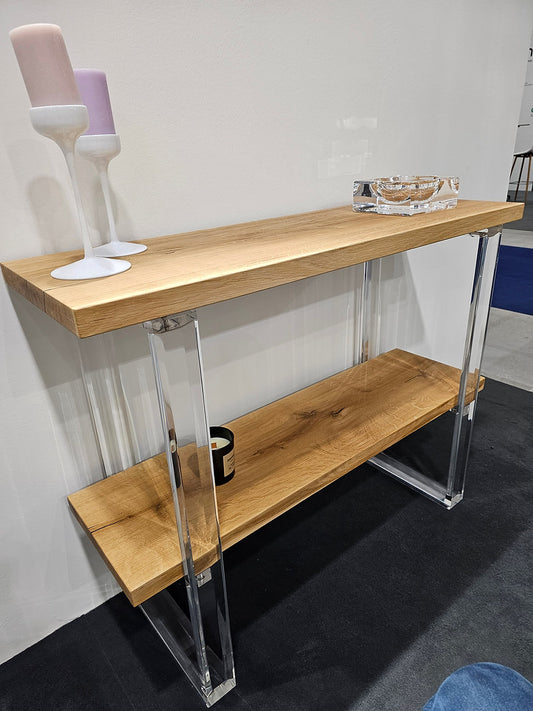 Clear acrylic console table with a light wood top and shelf