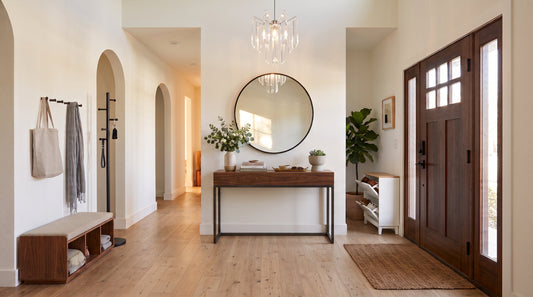 A modern entryway furniture ideas featuring a console table, round mirror, white shoe rack, bench, and acrylic chandelier