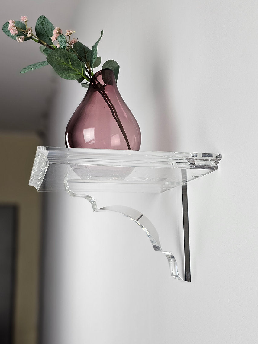 A clear acrylic floating shelf with a single mounting bracket