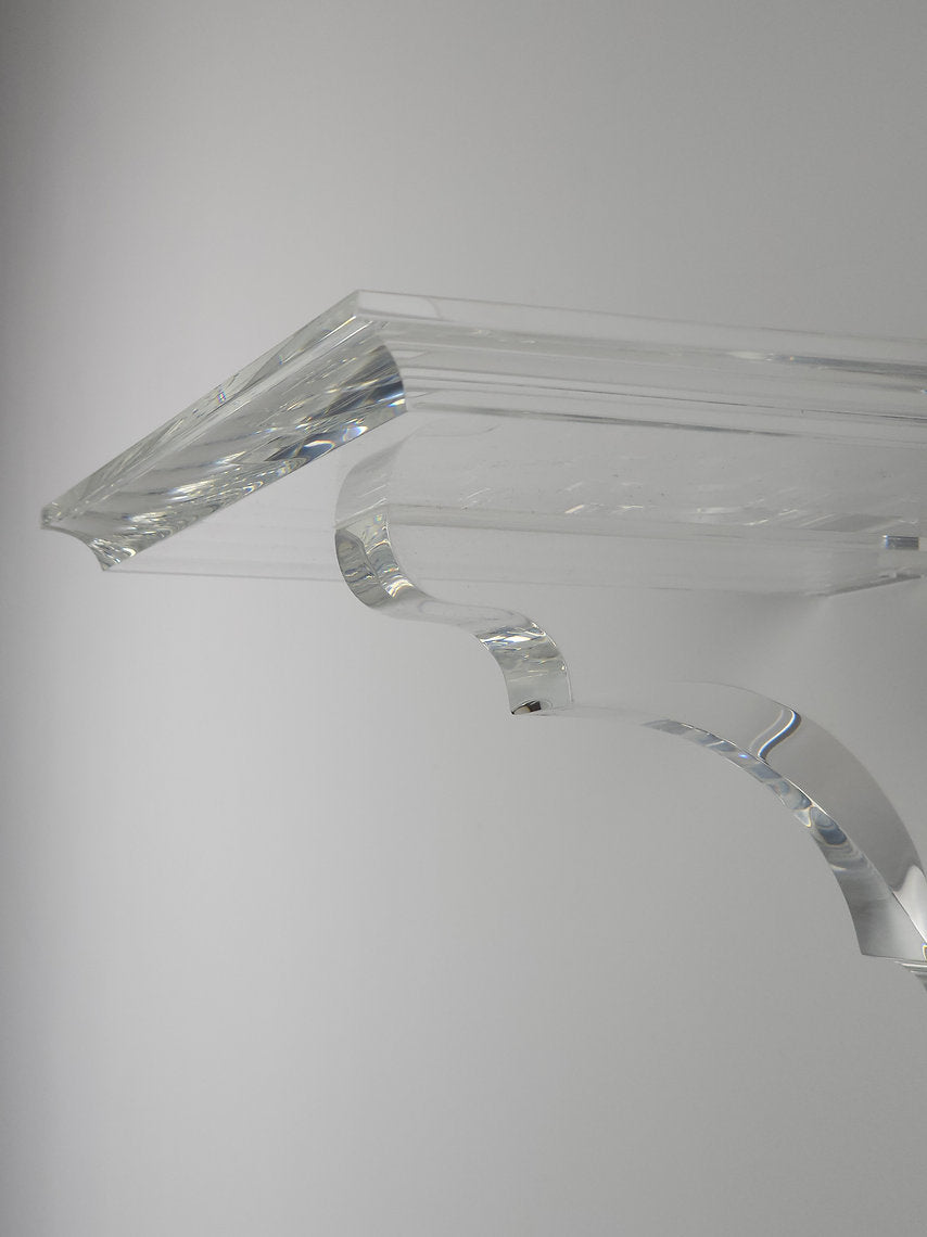 A clear acrylic floating shelf with a single mounting bracket