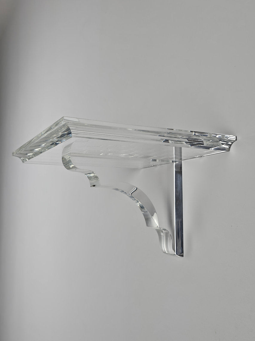 A clear acrylic floating shelf with a single mounting bracket