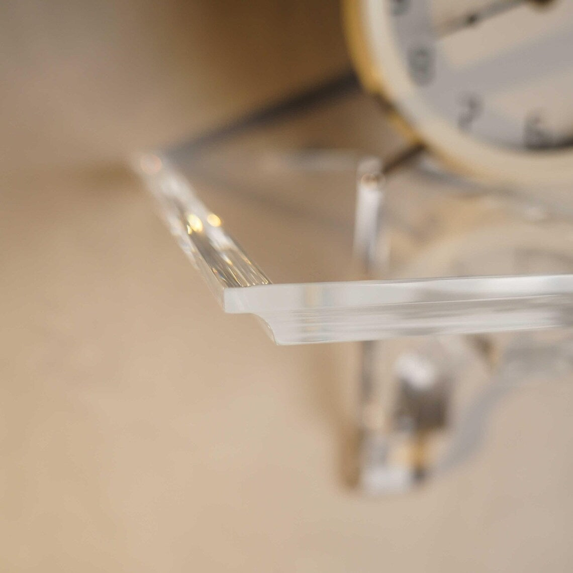 A clear acrylic floating shelf with a single mounting bracket