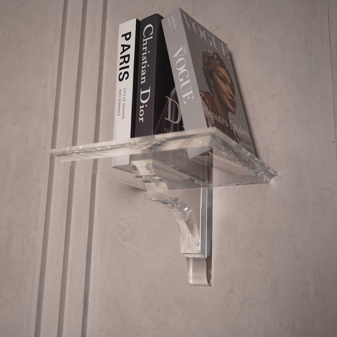 A clear acrylic floating shelf with a single mounting bracket