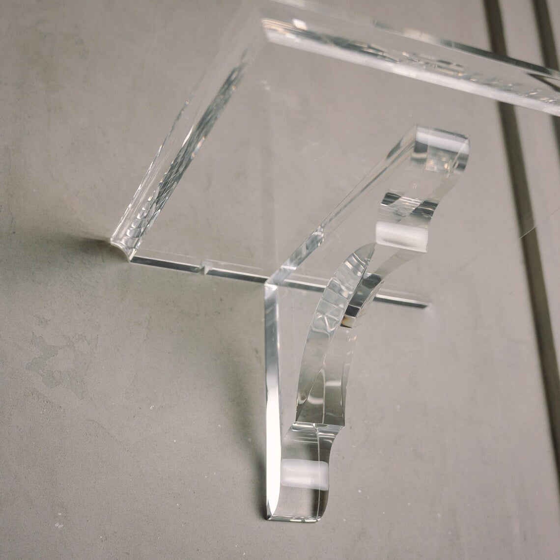 A clear acrylic floating shelf with a single mounting bracket