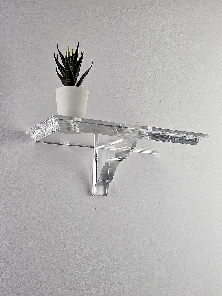 A clear acrylic floating shelf with a single mounting bracket