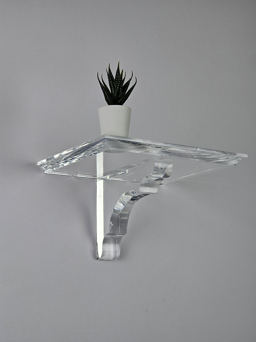 A clear acrylic floating shelf with a single mounting bracket