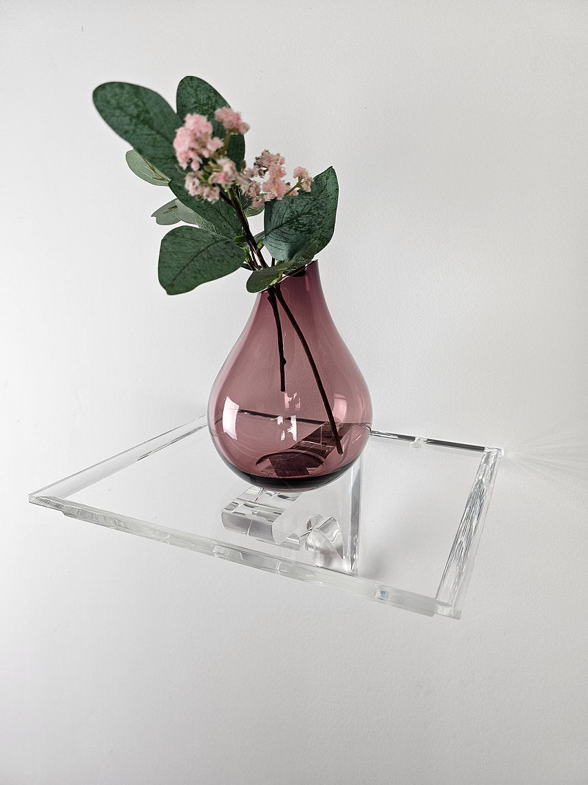 A clear acrylic floating shelf with a single mounting bracket