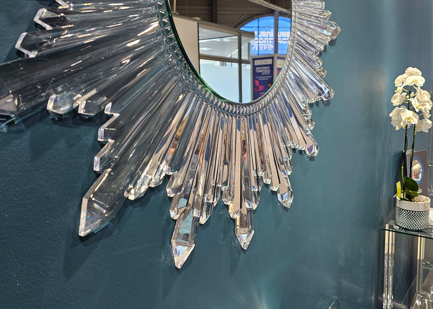 Circular sunburst wall mirror with clear acrylic crystals radiating from the center