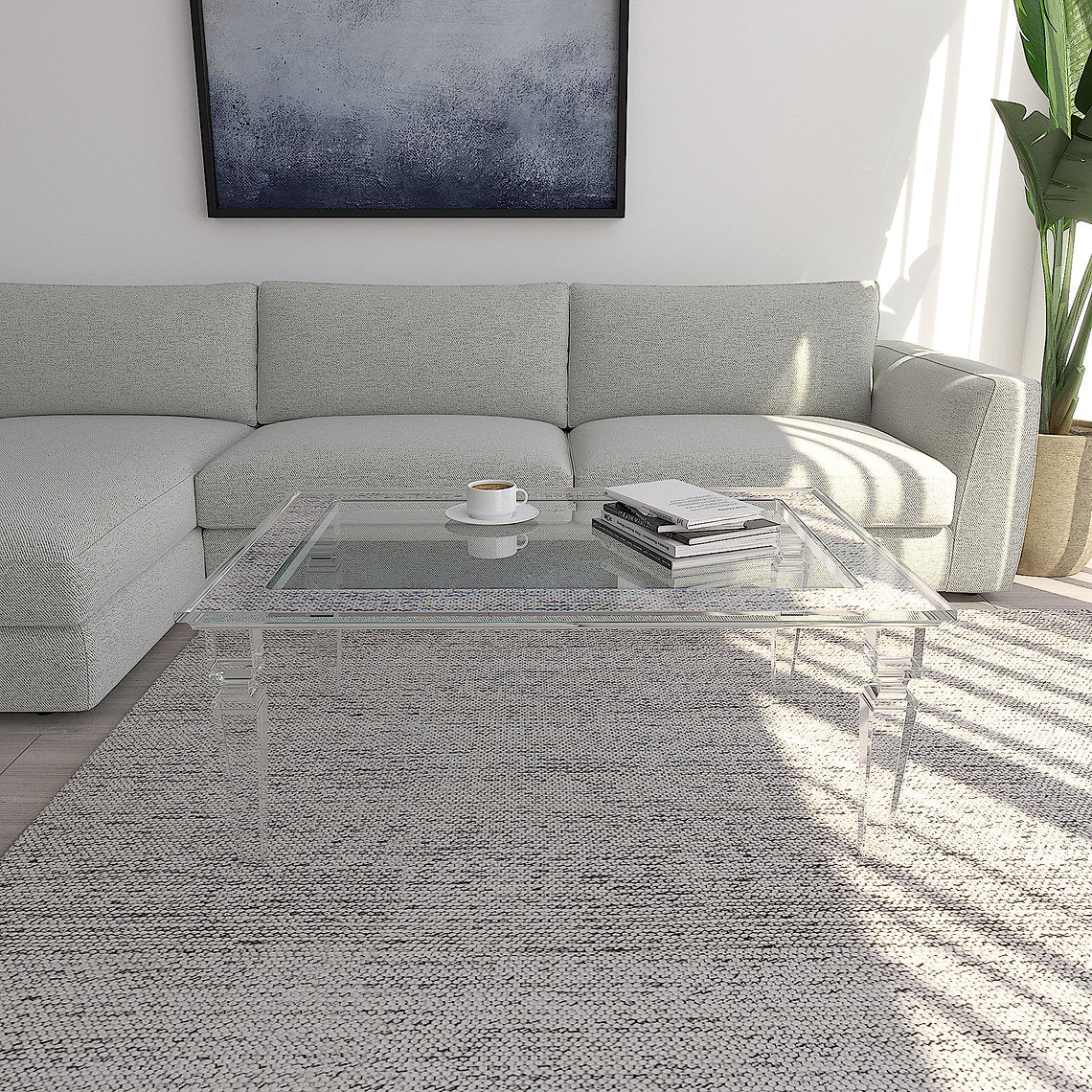 Modern living room with a gray sectional sofa, glass coffee table, and abstract painting.