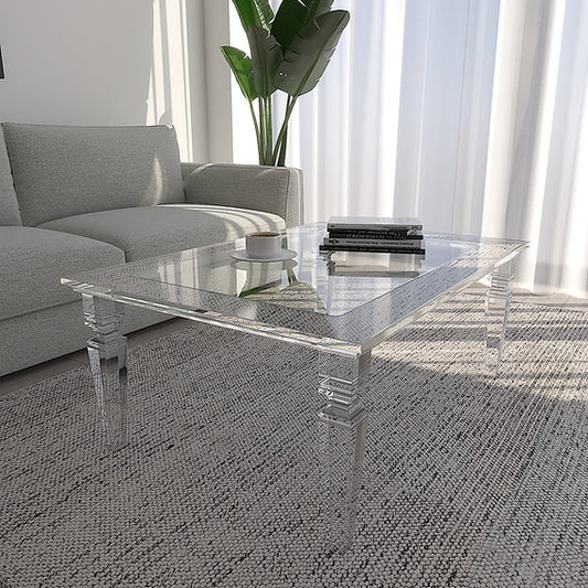Clear acrylic coffee table in a living room with a gray sofa and white curtains.