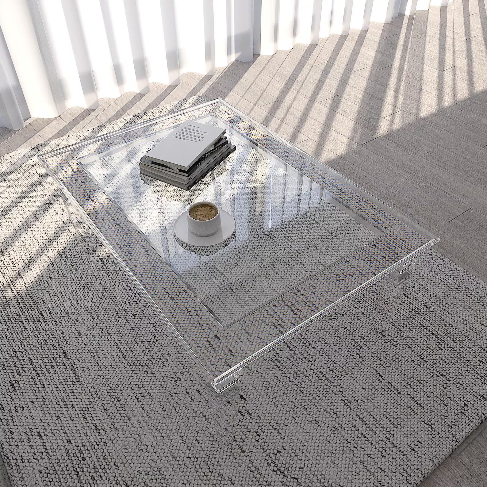 Clear acrylic coffee table with a few items on it, placed on a textured rug.